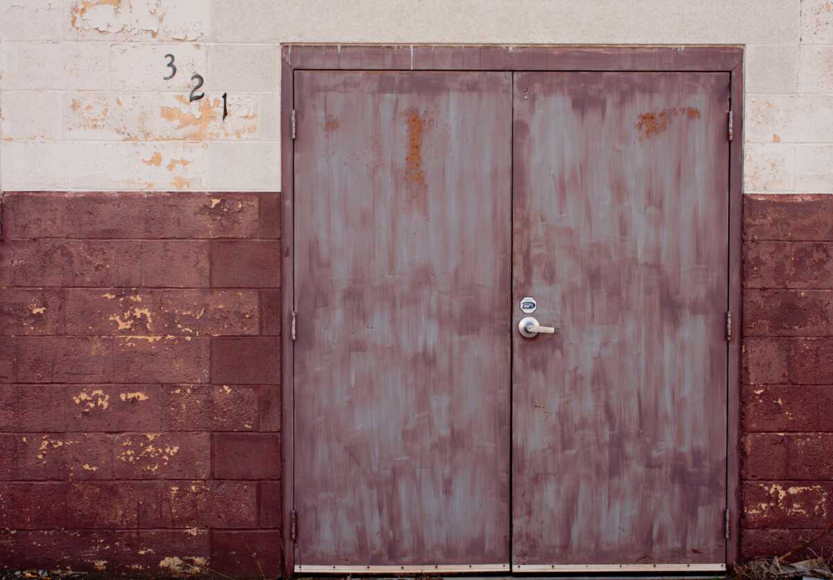Double metal doors with numbers 321 above, on a brick wall.
