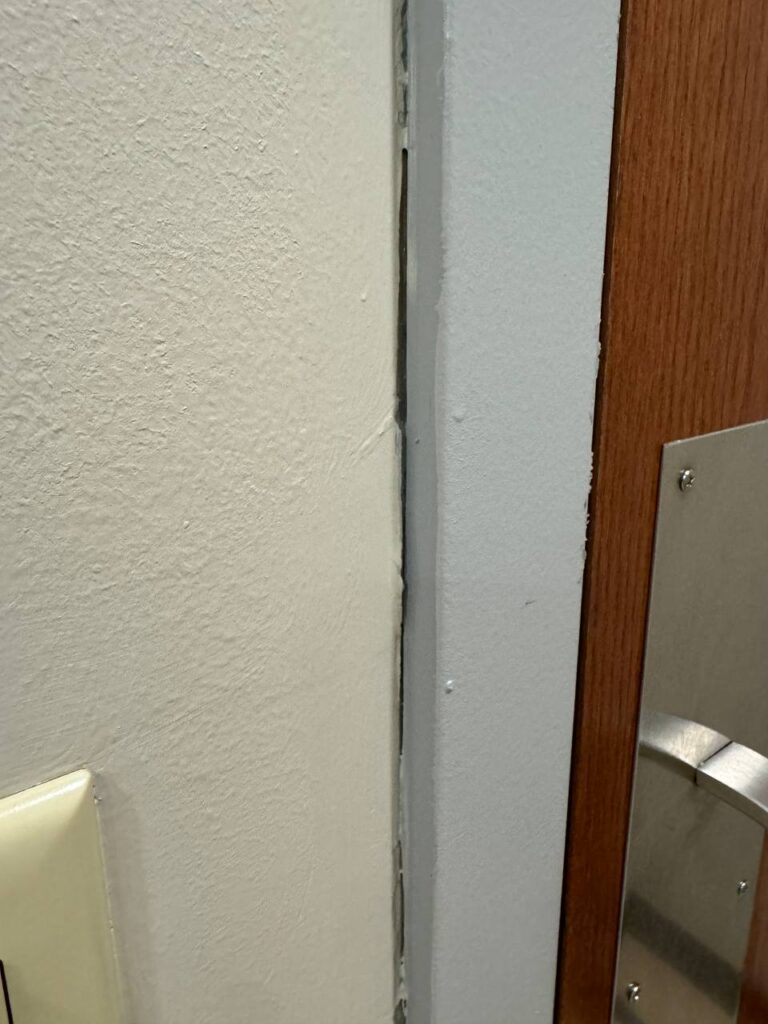 Gap between wall and door frame, indicating poor painting job