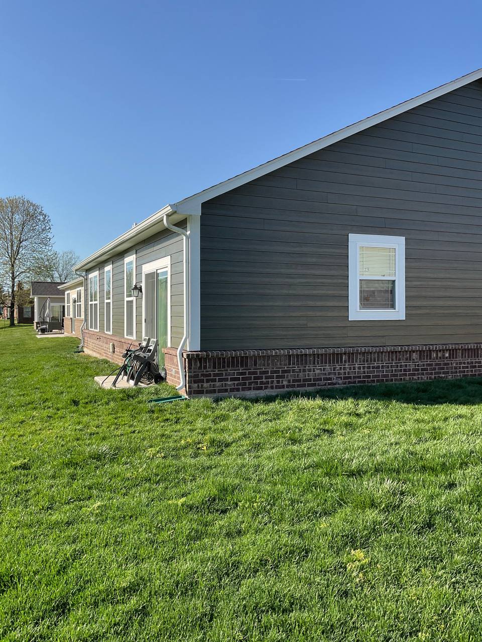 Exterior of a modern home with dark gray siding and brick foundation