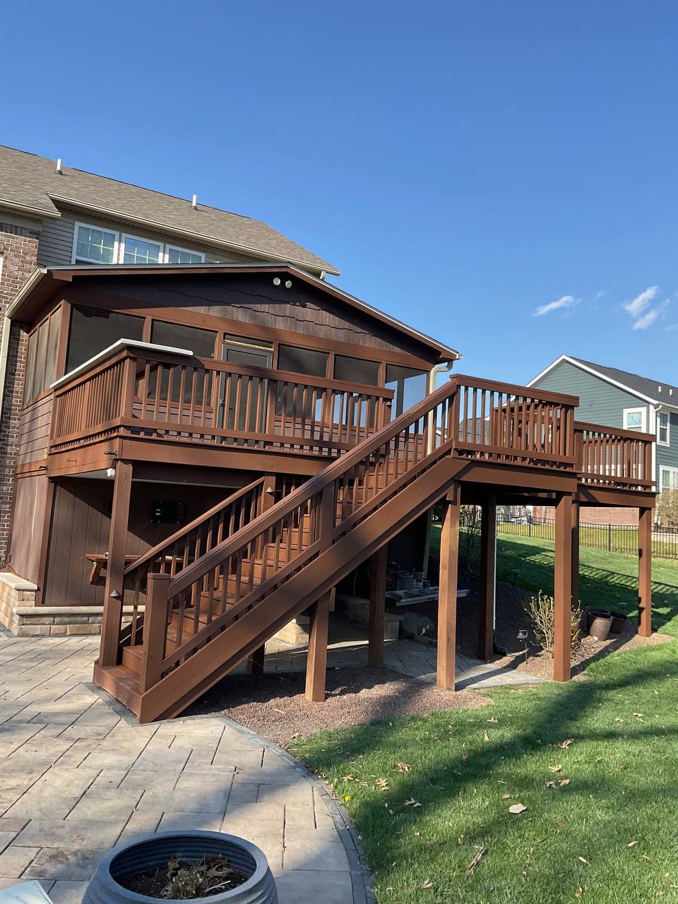 Newly stained wooden deck and screened porch addition on a suburban home