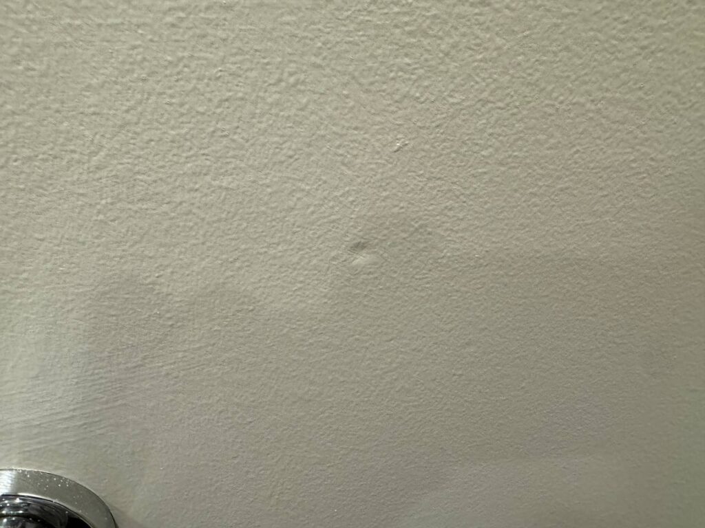 Close-up of a textured, painted wall with a small imperfection