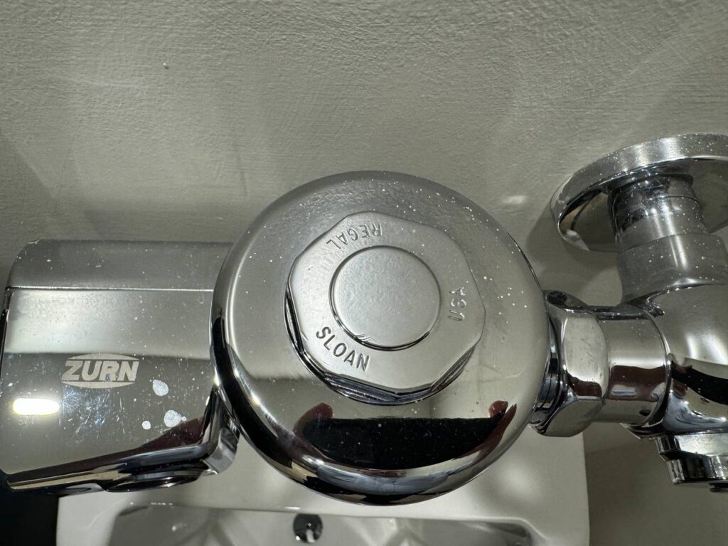 Chrome Zurn and Sloan flushometer valve, possibly for a toilet or urinal.