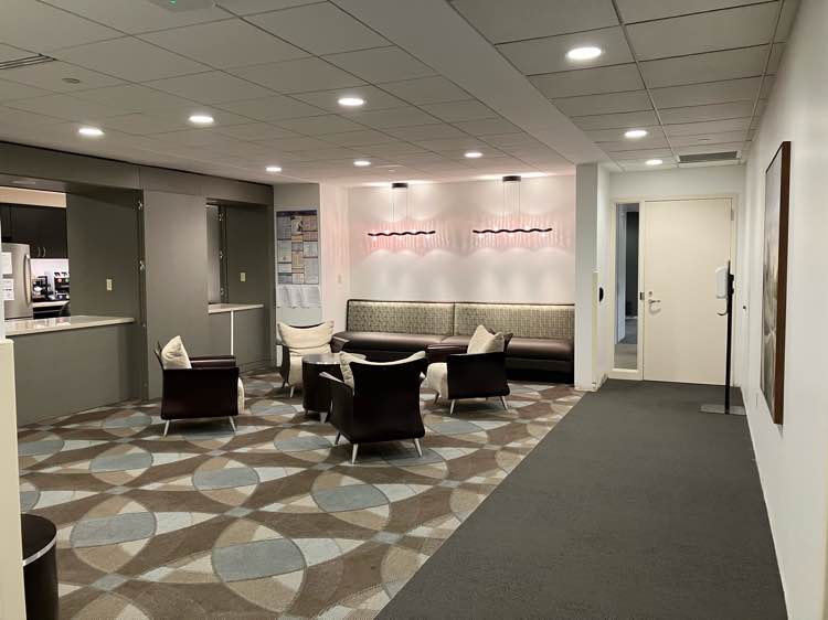 Modern office lounge area with comfortable seating and abstract carpet design.