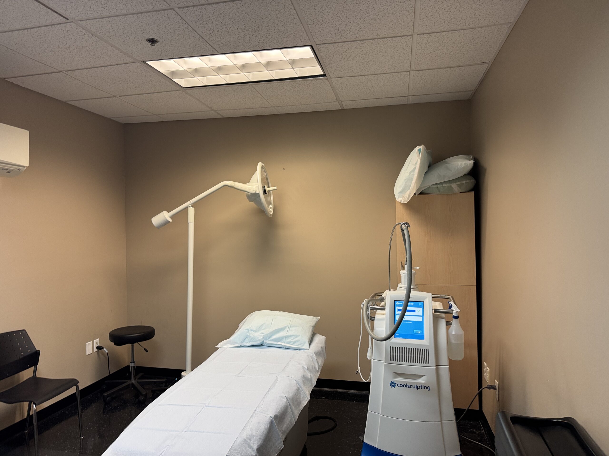 CoolSculpting machine and treatment bed in a medical spa room.