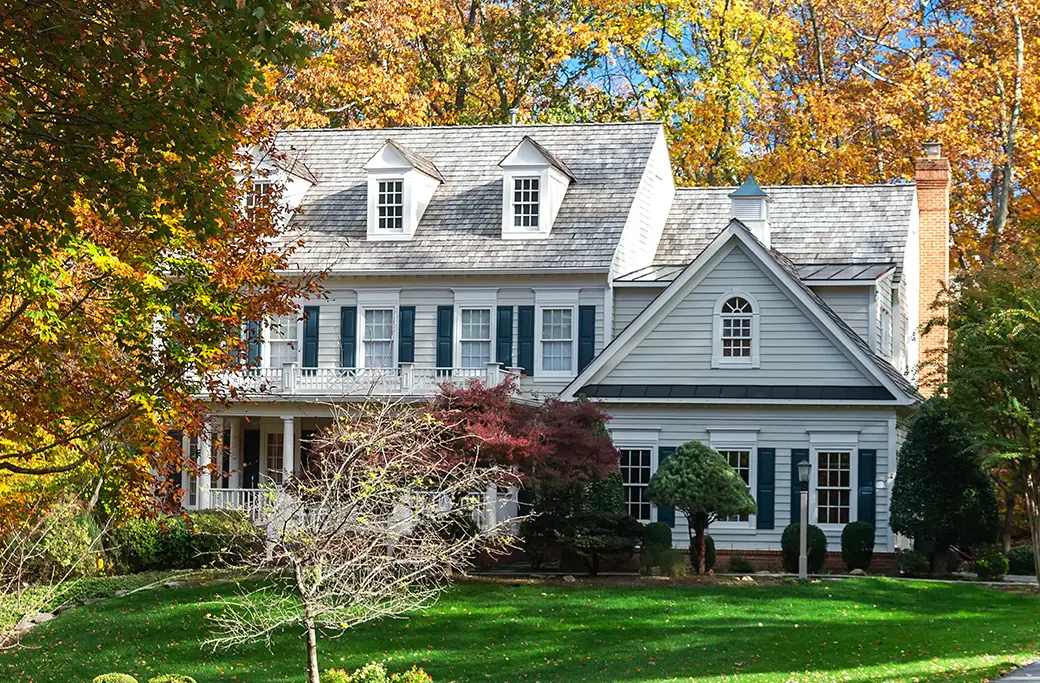 Light blue house with dark shutters surrounded by fall foliage in Indiana