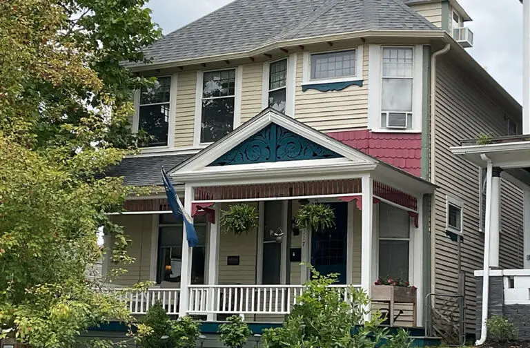 Victorian home with yellow siding, red accents, and a welcoming porch
