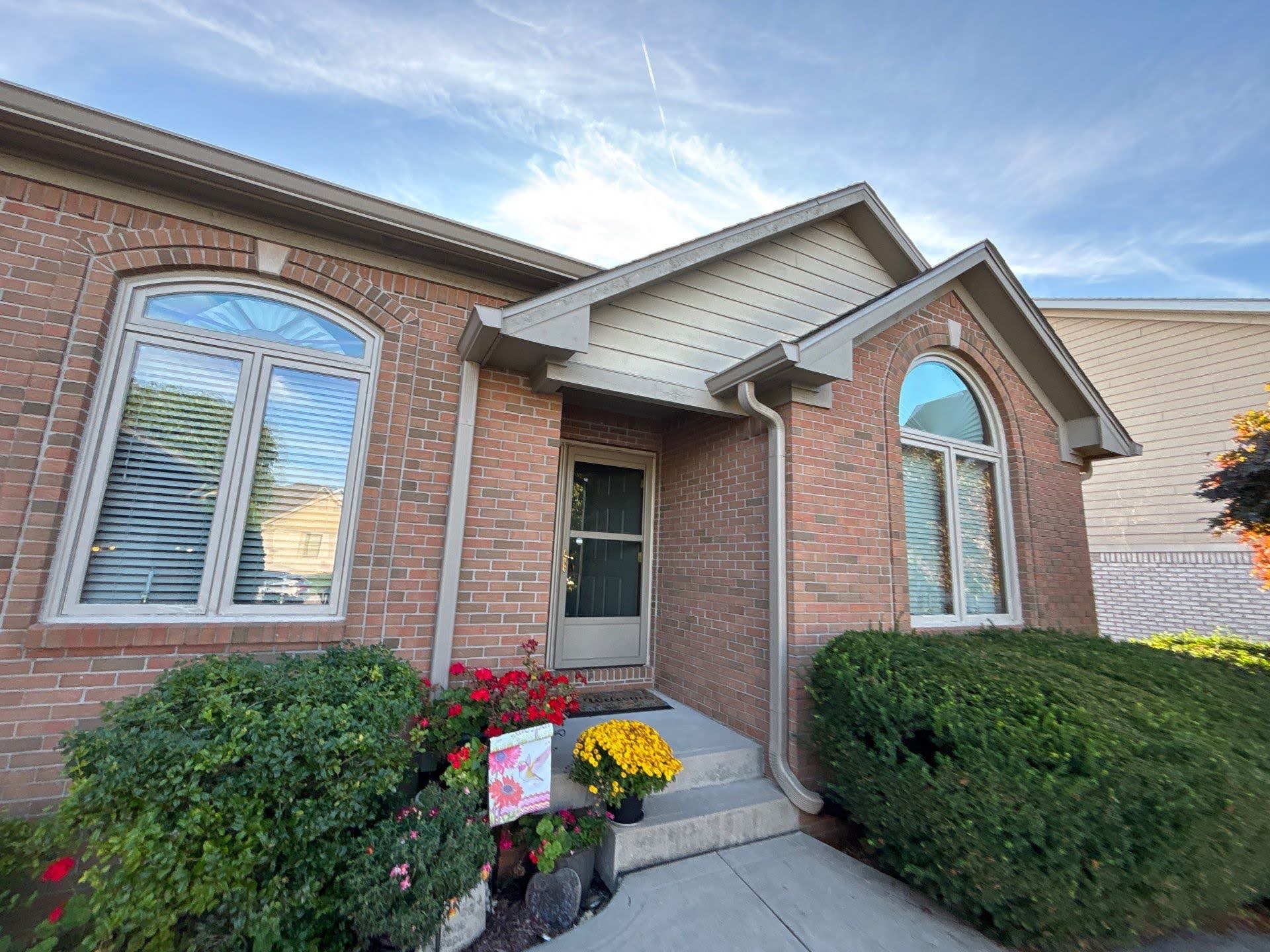 Brick House Front Door With Flowers Exterior of Lawton Residence with brick facade and arched windows.