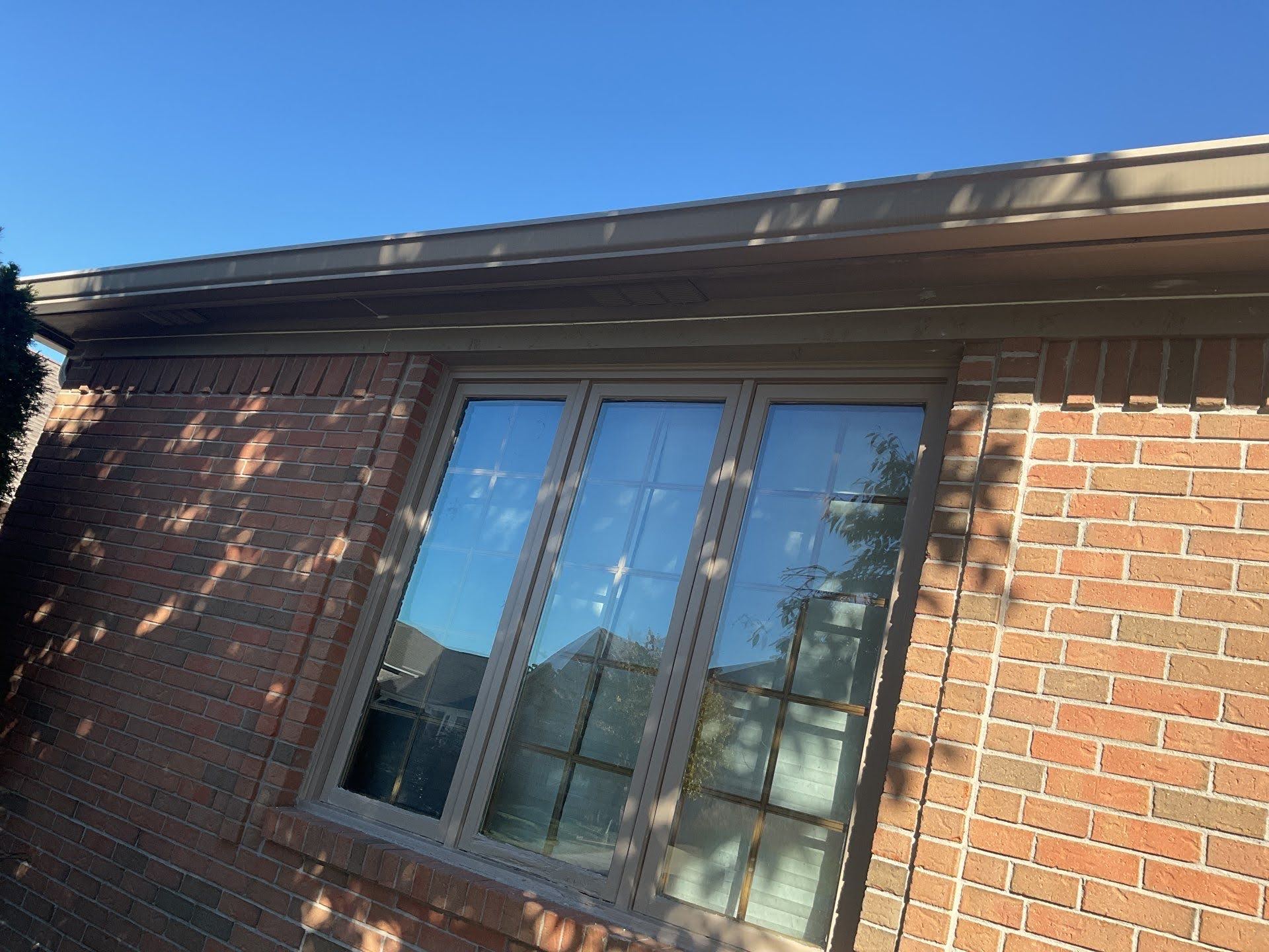 Brick House Window Reflection Lawton Residence exterior: brick wall, window, and tan trim.