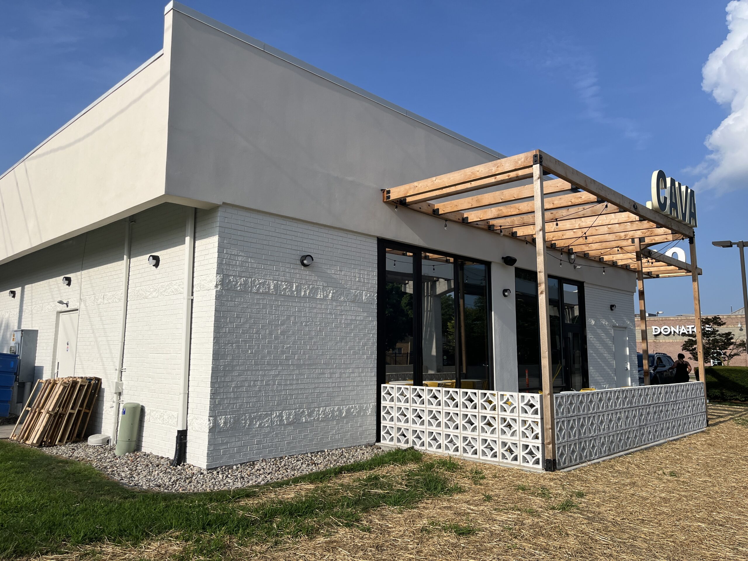 Cava Restaurant Exterior White Brick Patio Cava canopy exterior with white brick and wooden pergola structure.