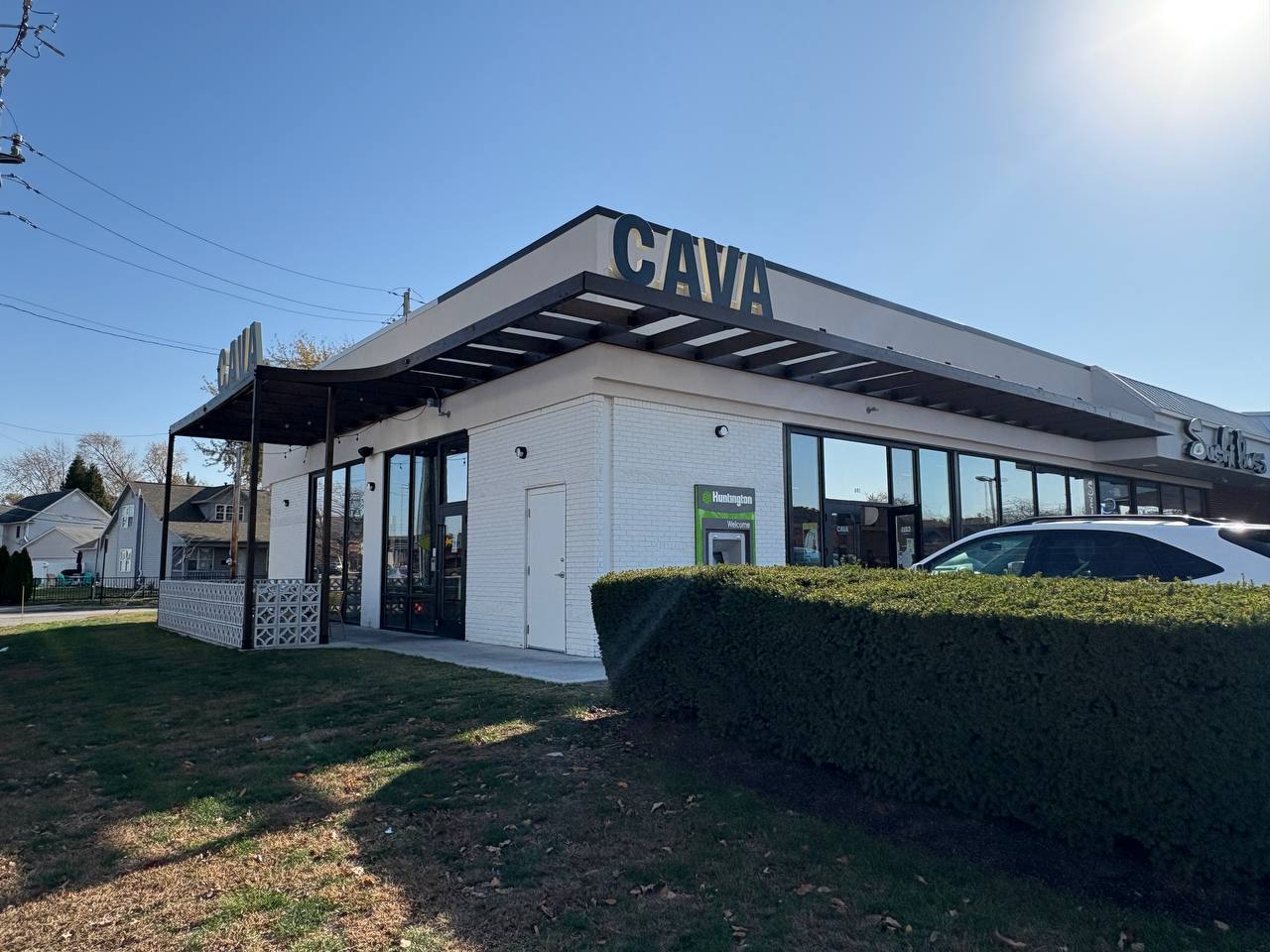 Cava Restaurant Exterior With Huntington Bank Atm CAVA restaurant exterior with a modern canopy and green landscaping.