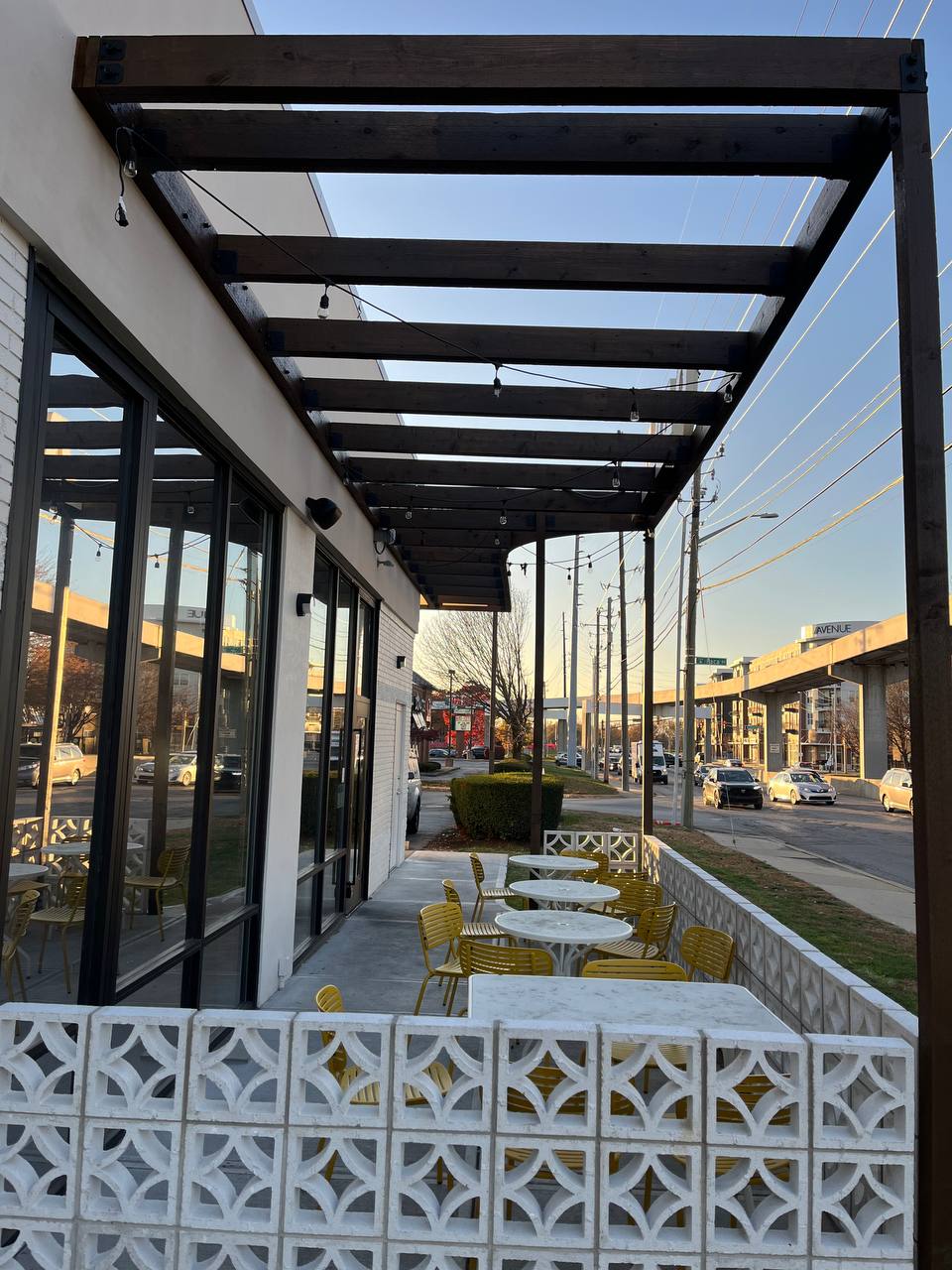 Outdoor Cafe Seating With Pergola Exterior view of Cava restaurant with wooden canopy, tables, and chairs.