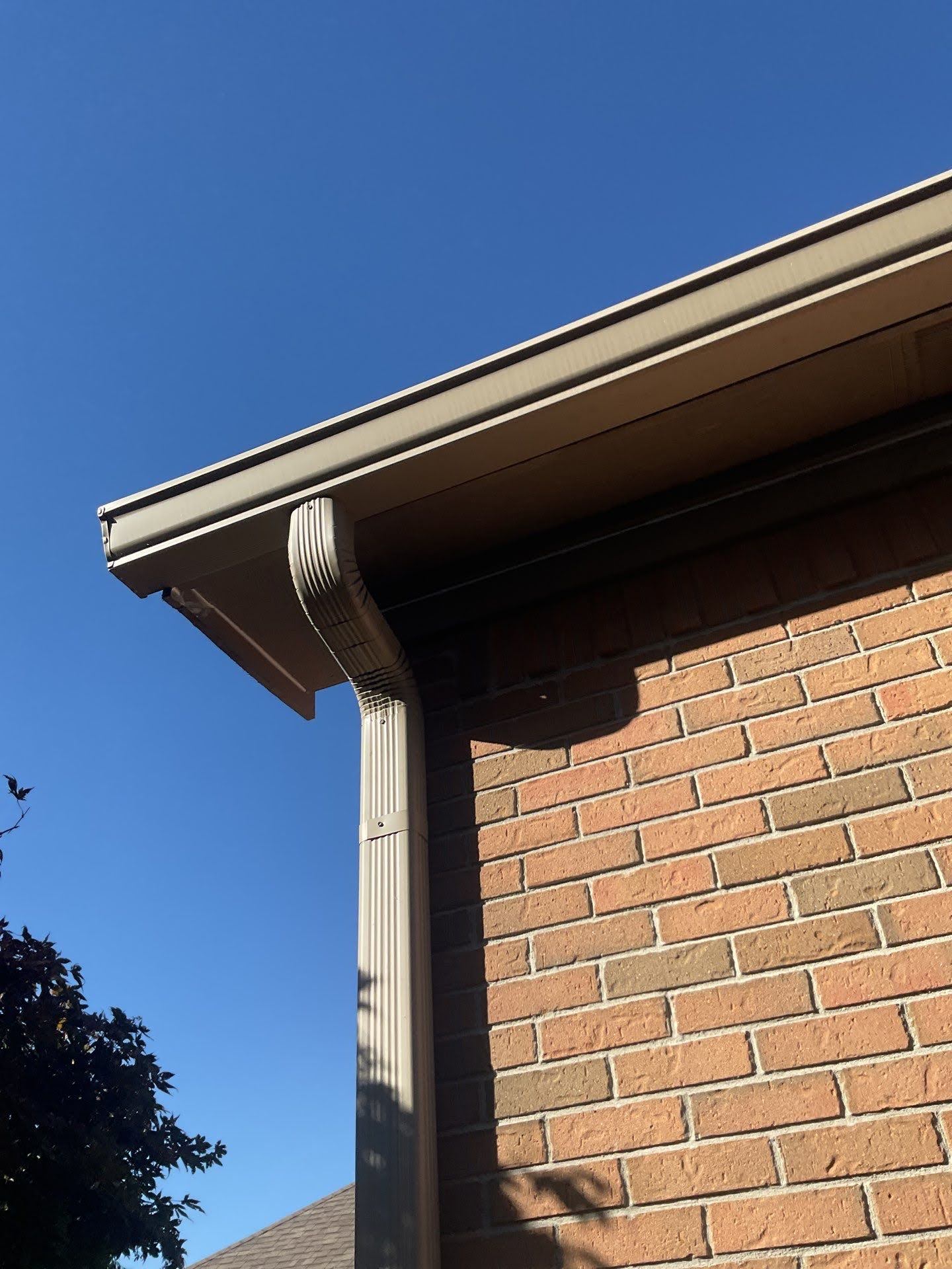 Tan Gutter Downspout On Brick House Lawton Residence exterior painting: close-up of tan gutters and downspout on brick house.