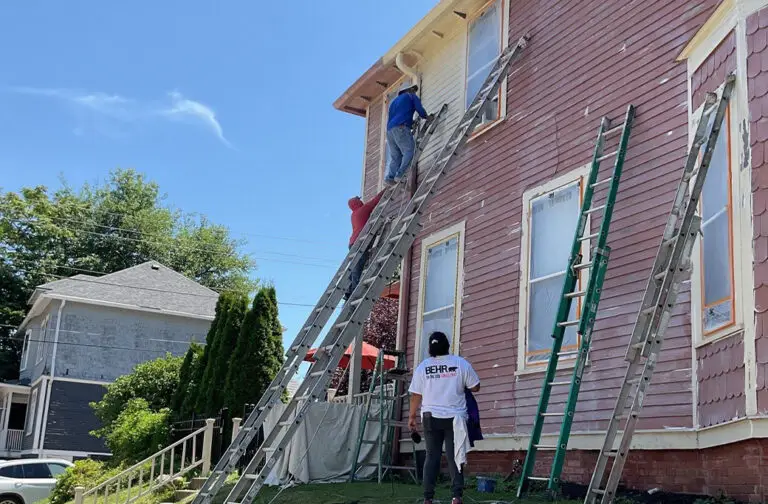 Professional exterior house painter applying fresh paint to an Indiana home
