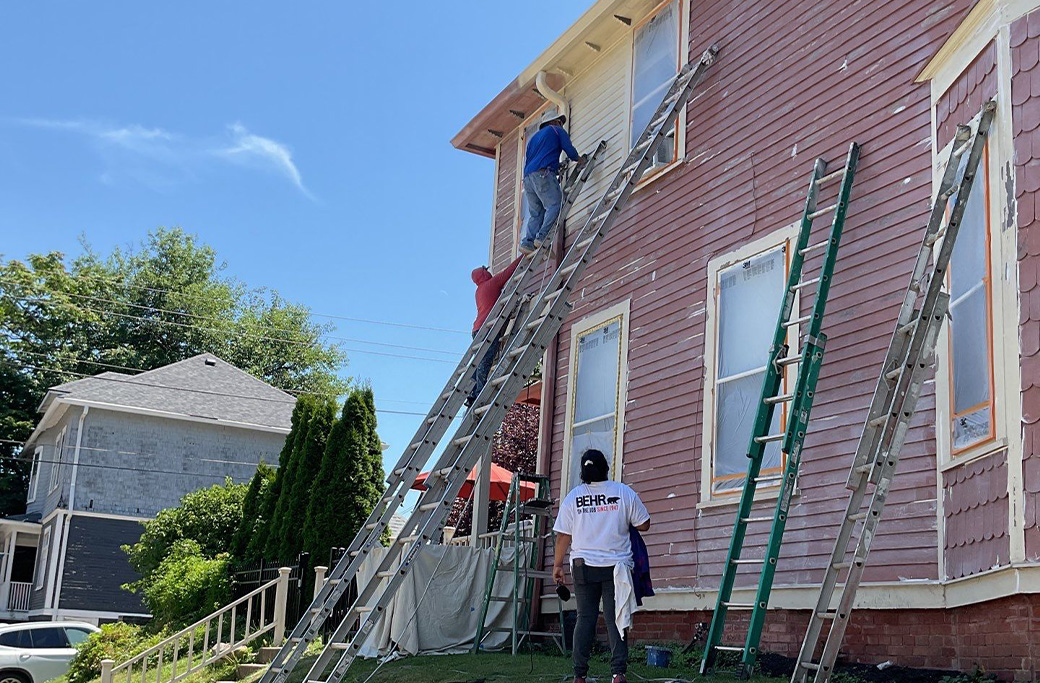 Professional exterior house painter applying fresh paint to an Indiana home