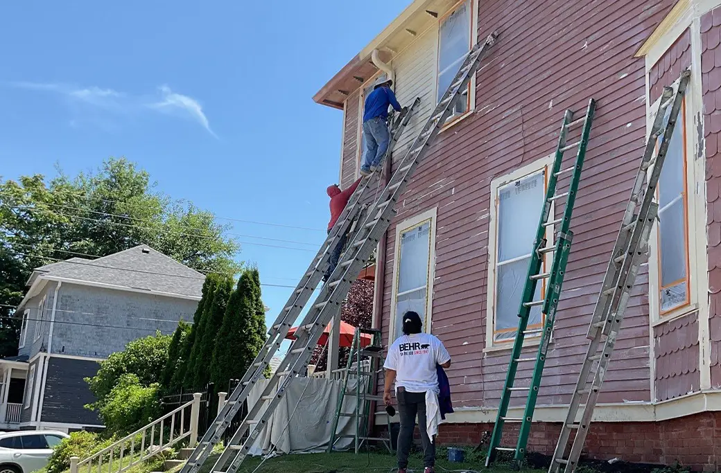 Professional exterior house painter applying fresh paint to an Indiana home