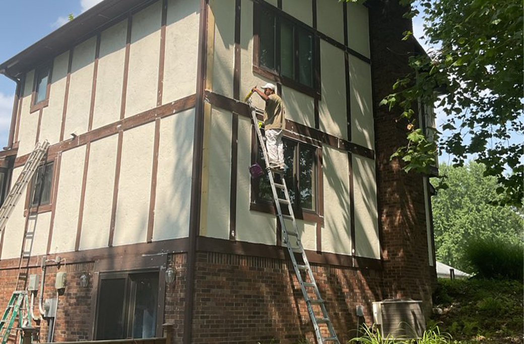 Professional painters working on a two-story home exterior painting project in Indiana