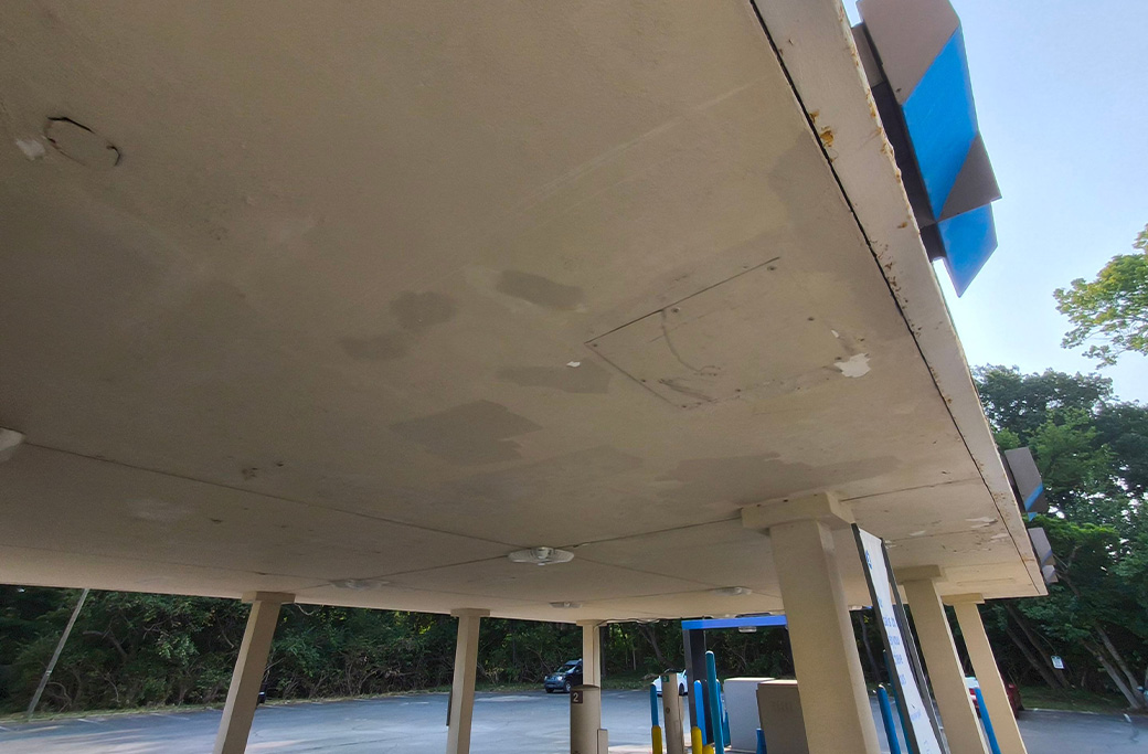 Peeling exterior paint and rust spots on a commercial building showing signs it needs repainting