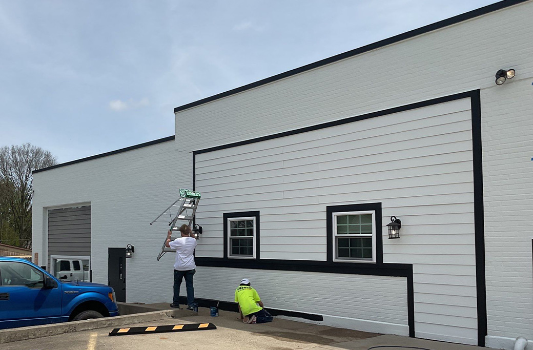 Commercial painters preparing a building surface before applying a new protective coating