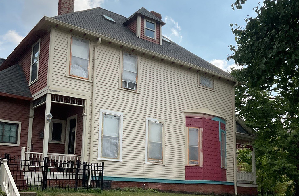 Exterior painting preparation work showing a partially painted Indiana home