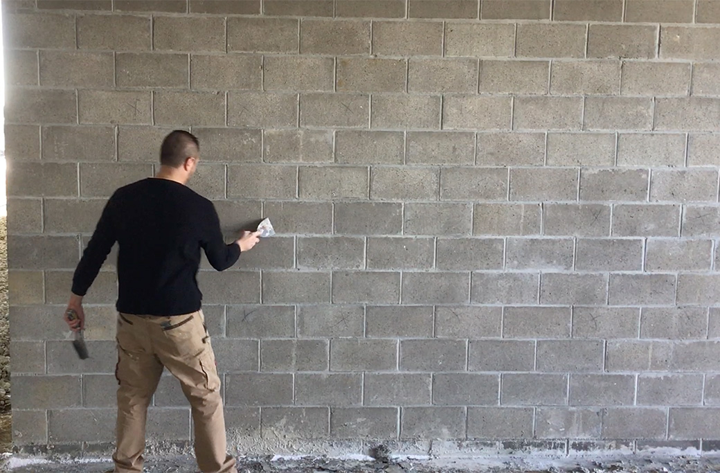 Man patching concrete block wall, potentially for commercial siding repair.