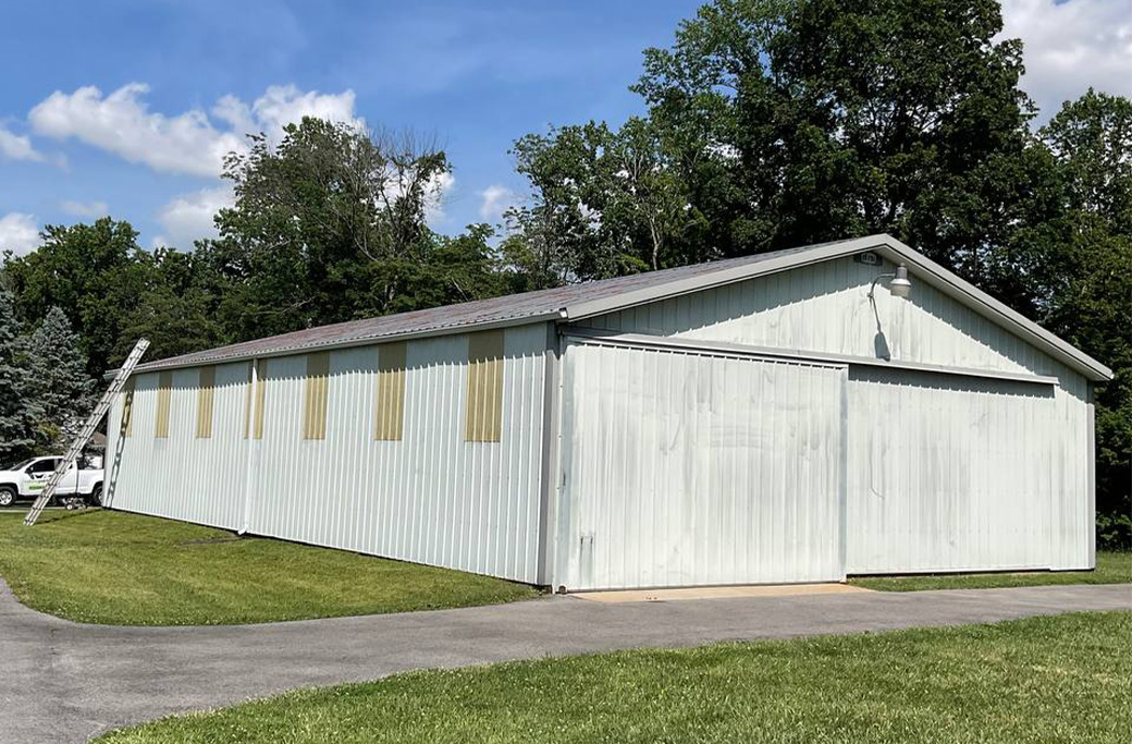 White corrugated metal commercial building siding needs repair or painting.