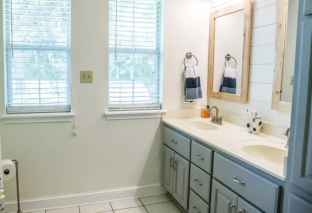 Residential bathroom with double vanity and light gray cabinets