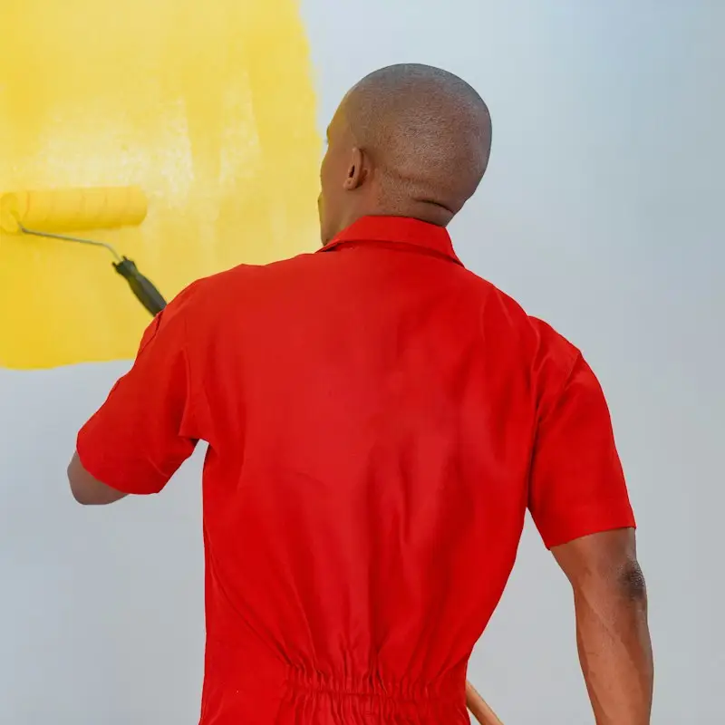 Painter rolling bright yellow paint onto an interior wall