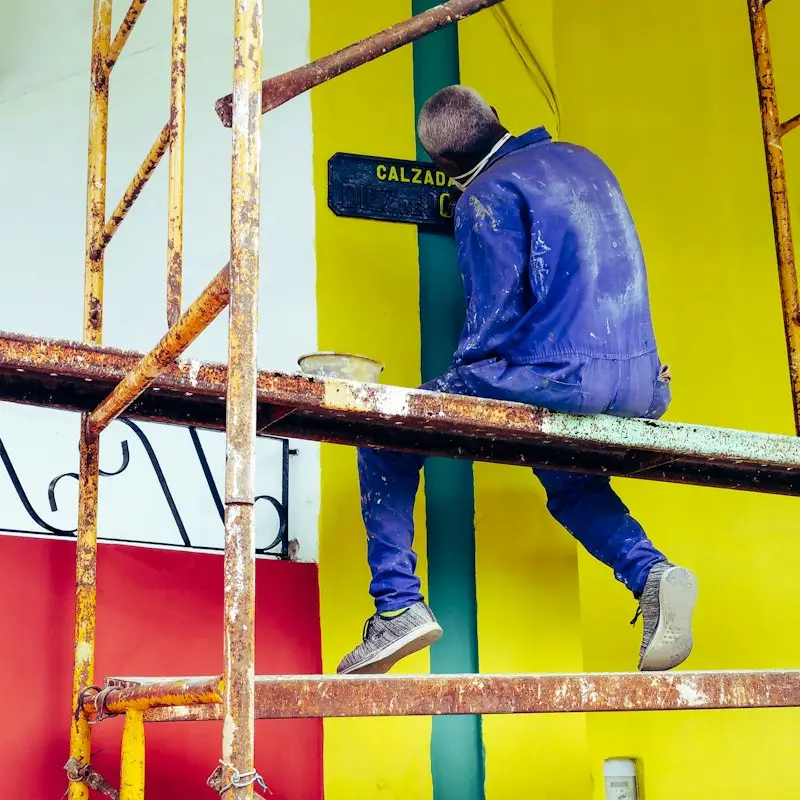 Painter working on scaffolding on a bright commercial wall
