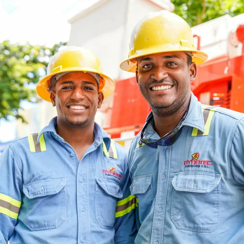 Two smiling tradesmen in hard hats standing together