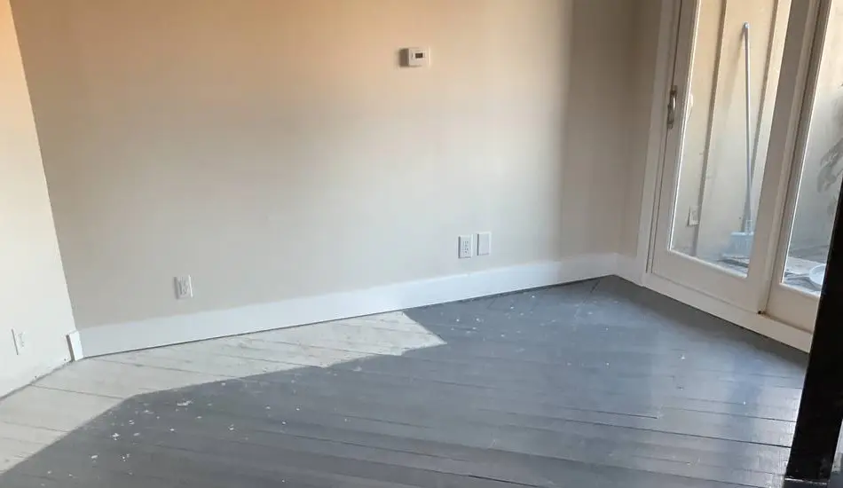 Newly painted room with gray floor, ready for rental turnover.