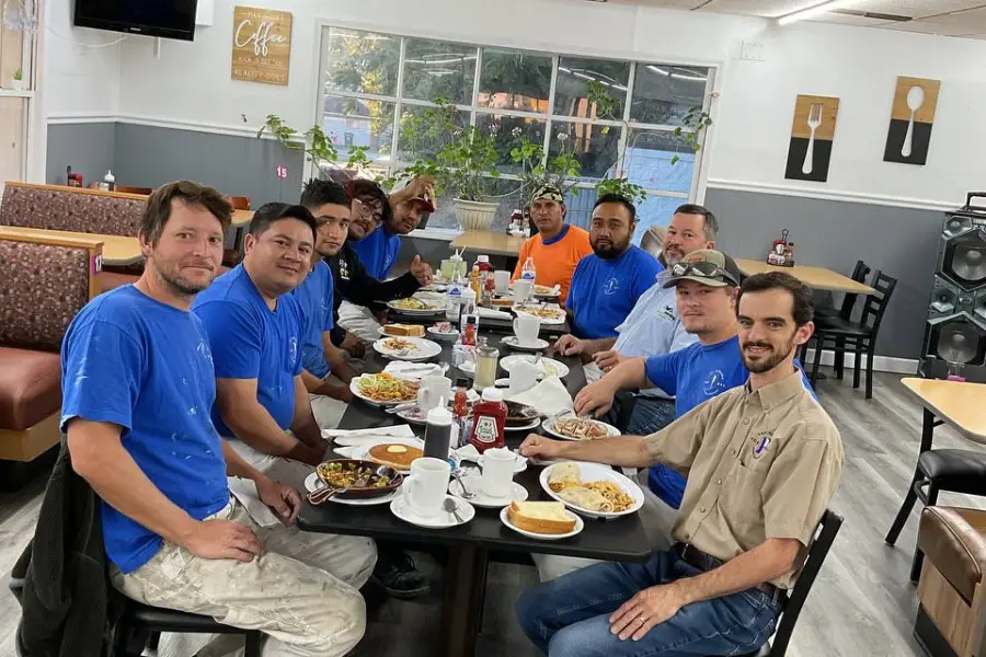 Team of painters in blue shirts enjoying a meal together